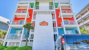 A multi-story hotel with balconies, a central sign, and a parking area. - Compass Rose 32, three-bedroom, two-bath oceanfront condo, Wi-Fi (Garden City Beach)