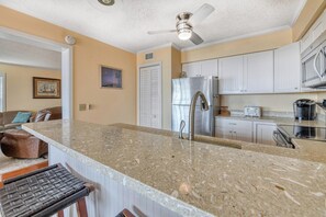 A kitchen with a granite countertop, stainless steel appliances, and white cabinetry.