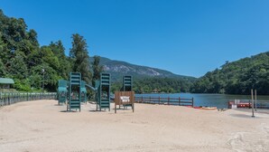 Une zone de plage sablonneuse avec une aire de jeux et un panneau indiquant « Bataille d’eau ».