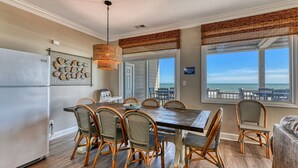 A dining area with a wooden table and wicker chairs, large windows with ocean views, and a ceiling fan. - Doctor's RX - Six Bedroom, Six Bath, Oceanfront Duplex with Private Pool (Myrtle Beach)