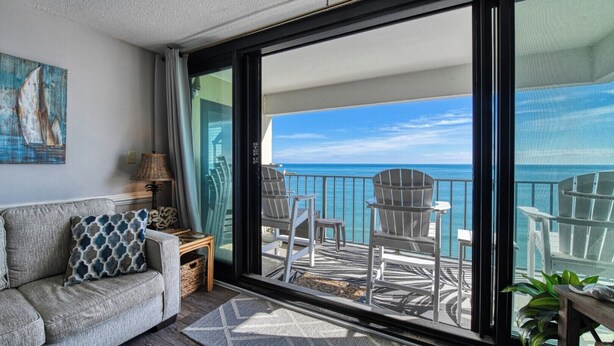 Een balkon met uitzicht op zee, voorzien van stoelen en een tafel.