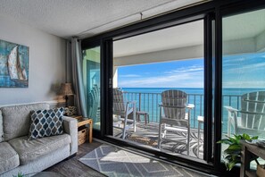 Un balcon avec vue sur l’océan, aménagé avec des chaises et une table.