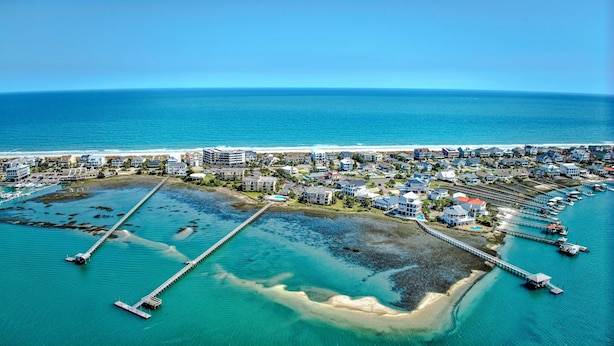 An aerial view of a coastal resort with multiple buildings, a marina, and a pier extending into the water. - Inlet Pointe 30 Inlet front condo with pool, fishing dock and Walk to beach (Garden City Beach)