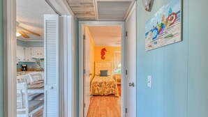 A narrow hallway leading to a bedroom with a bed, a nightstand, and a painting on the wall. - Inlet Pointe 33, two-bedroom, two-bath Inlet/channel-front condo (Garden City Beach)
