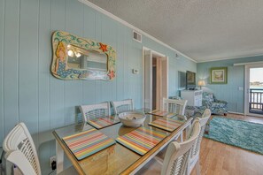 A dining area with a wooden table, striped placemats, white chairs, and a decorative mirror with a starfish design. - Inlet Pointe 33, two-bedroom, two-bath Inlet/channel-front condo (Garden City Beach)