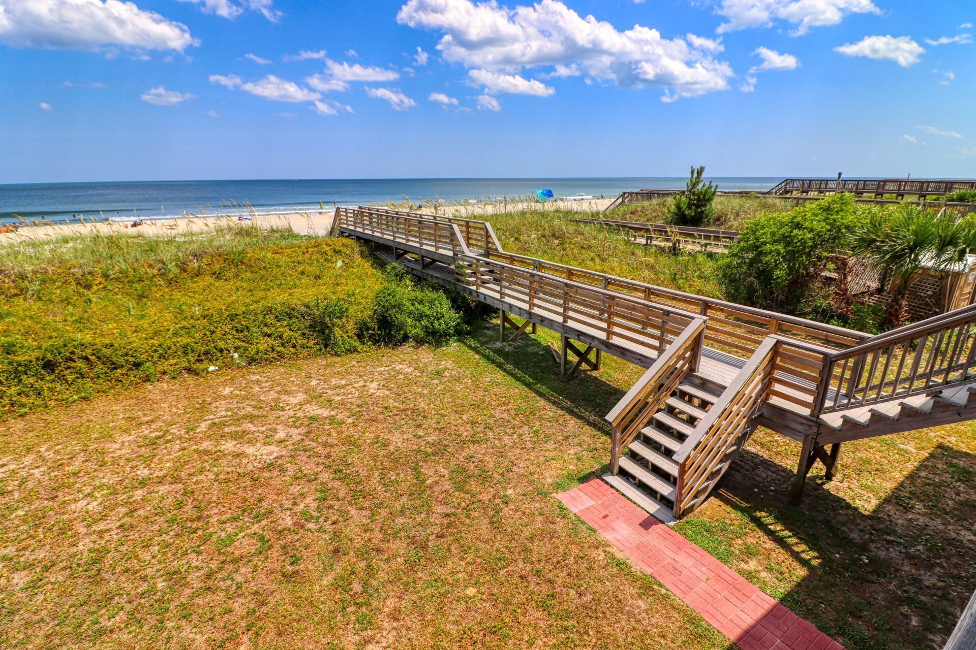 A wooden boardwalk leading to a beach with a clear view of the ocean.