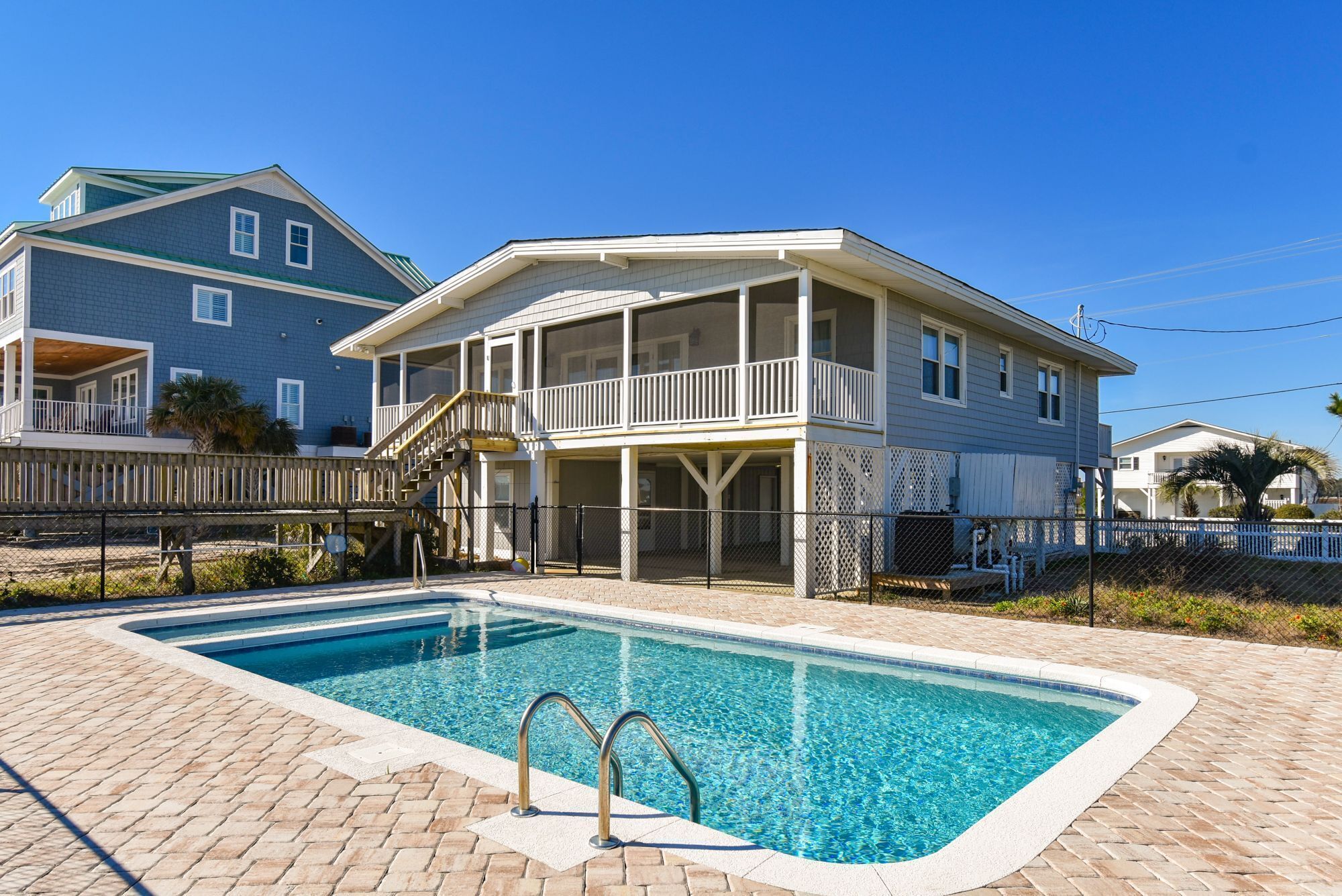 A two-story house with a swimming pool, a covered deck, and a fenced yard.
