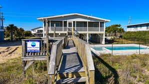 A two-story house with a wooden deck leading to a private pool. - Lazy O - Four Bedroom, Three 1/2 Bath Oceanfront Home with Private Pool (Garden City Beach)