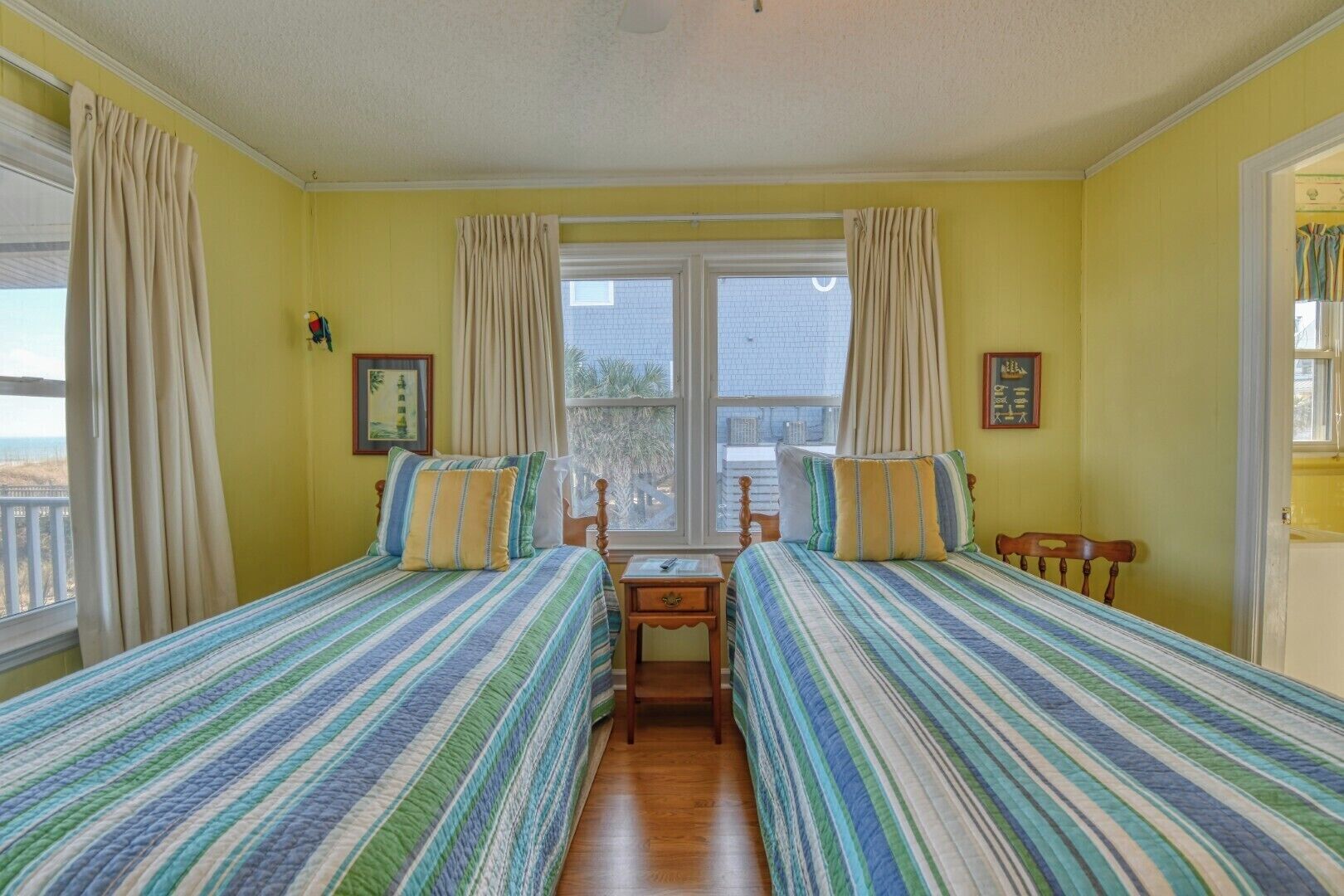 A room with two beds, a window with curtains, and a small table.