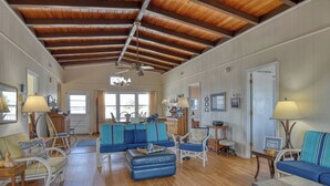 A spacious living room with a high wooden ceiling, a blue sofa set, and a dining area with a table and chairs. - Lazy O - Four Bedroom, Three 1/2 Bath Oceanfront Home with Private Pool (Garden City Beach)