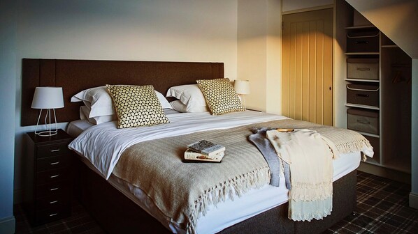 A neatly made bed with patterned pillows, a bedside lamp, and a book on the bed.