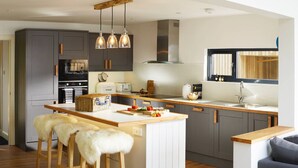 Une cuisine moderne avec des meubles gris, un îlot central en bois et un four encastré.