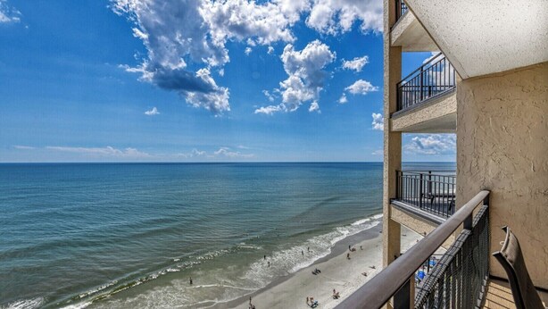 A balcony with a view of a beach and ocean.