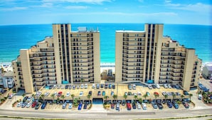 Um hotel moderno com vários andares, pátio central, diversos níveis de estacionamento e vista para a praia.