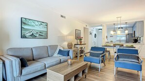 Ein modernes Wohnzimmer mit grauem Sofa, blauen Sesseln und einem Holztisch.