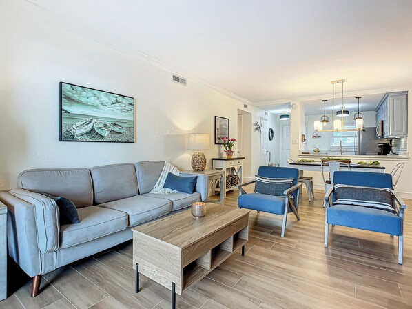 A modern living room with a grey sofa, blue armchairs, and a wooden coffee table.