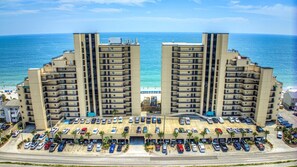 A high-rise hotel with multiple floors, a parking lot, and a view of the beach and ocean. - Surfmaster 108 - Three-bedroom, three-bath first-floor oceanfront condo (Garden City Beach)