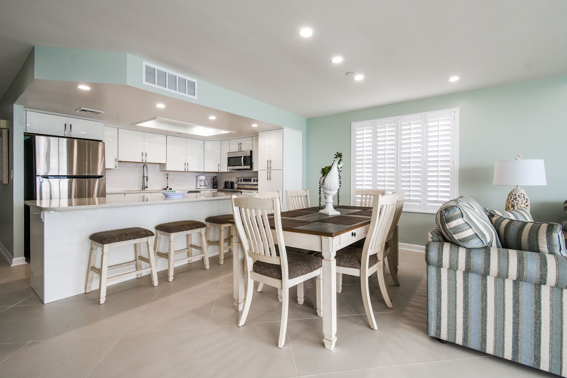 A modern kitchen with white cabinets, stainless steel appliances, and a central island with stools.