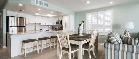 A modern kitchen with white cabinets, stainless steel appliances, and a central island with stools.
