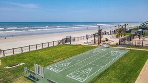 En grön shuffleboard-bana med utsikt över stranden och havet.