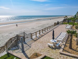 A beachside promenade with a paved walkway, sun loungers, and a railing overlooking the ocean. - Watch the sunrise over the No Drive Beach in NSB! (New Smyrna Beach)