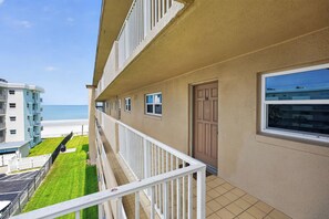 A residential building with a balcony overlooking a beach.