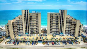 A high-rise hotel with a central courtyard, multiple parking levels, and a view of the beach.