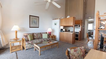 Una sala de estar con sofá, mesa de centro y sillas, una kitchenette, y un comedor con sillas y una mesa.