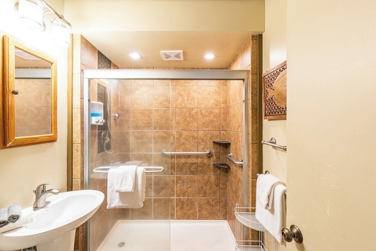 A bathroom with a glass-enclosed shower, a sink, and a toilet.