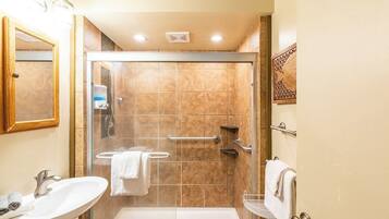 A bathroom with a glass-enclosed shower, a sink, and a toilet.