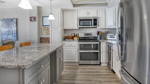 Una cocina moderna con electrodomésticos de acero inoxidable, armarios blancos y encimera de granito.