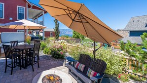 An outdoor patio with a fire pit, a wooden table with chairs, and a large umbrella. - Northern Lights at Chelan Lookout Vacation Rentals (Chelan)
