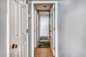 A hallway with white doors, a patterned rug, and a ceiling light fixture.