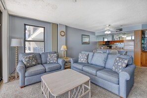A living room with two sofas, a coffee table, and a kitchen in the background.