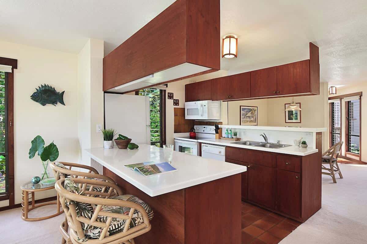 A modern kitchen with a central island, wooden cabinets, and a large window.