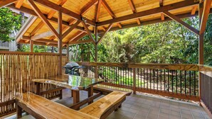 An outdoor patio with wooden tables and benches, surrounded by bamboo fencing and a view of a lush garden. - Waikomo #320 - 2 Bed in Poipu Lush Landscaping Walking distance to Beach & Pool (Koloa)
