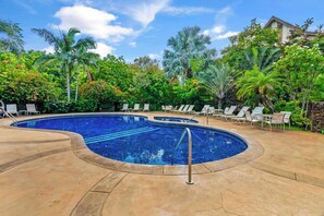Piscina com espreguiçadeiras e palmeiras.