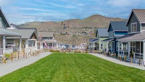 Una hilera de casas modernas con un césped al frente y un paisaje montañoso en el fondo.