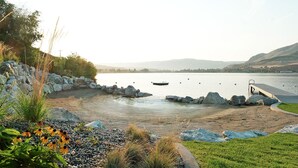 Vista de un lago con muelle, rocas y un bote.