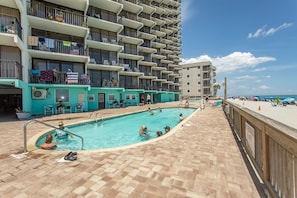 A rooftop pool area with a view of a high-rise building, a pool, and a beach in the background. - Immaculate, flawless two bedroom condo (Murrells Inlet)