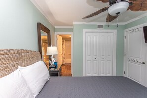 A bedroom with a bed, a ceiling fan, a door, and a nightstand with a lamp. - Immaculate, flawless two bedroom condo (Murrells Inlet)