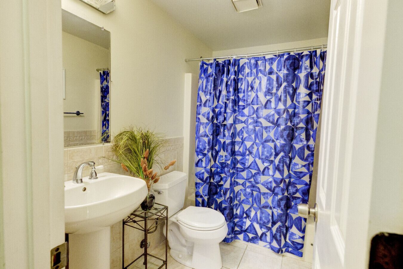 A bathroom with a white sink, toilet, and shower curtain with a geometric pattern.