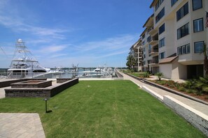 Un port de plaisance avec des bateaux, une zone herbeuse et un immeuble à plusieurs étages doté de balcons.