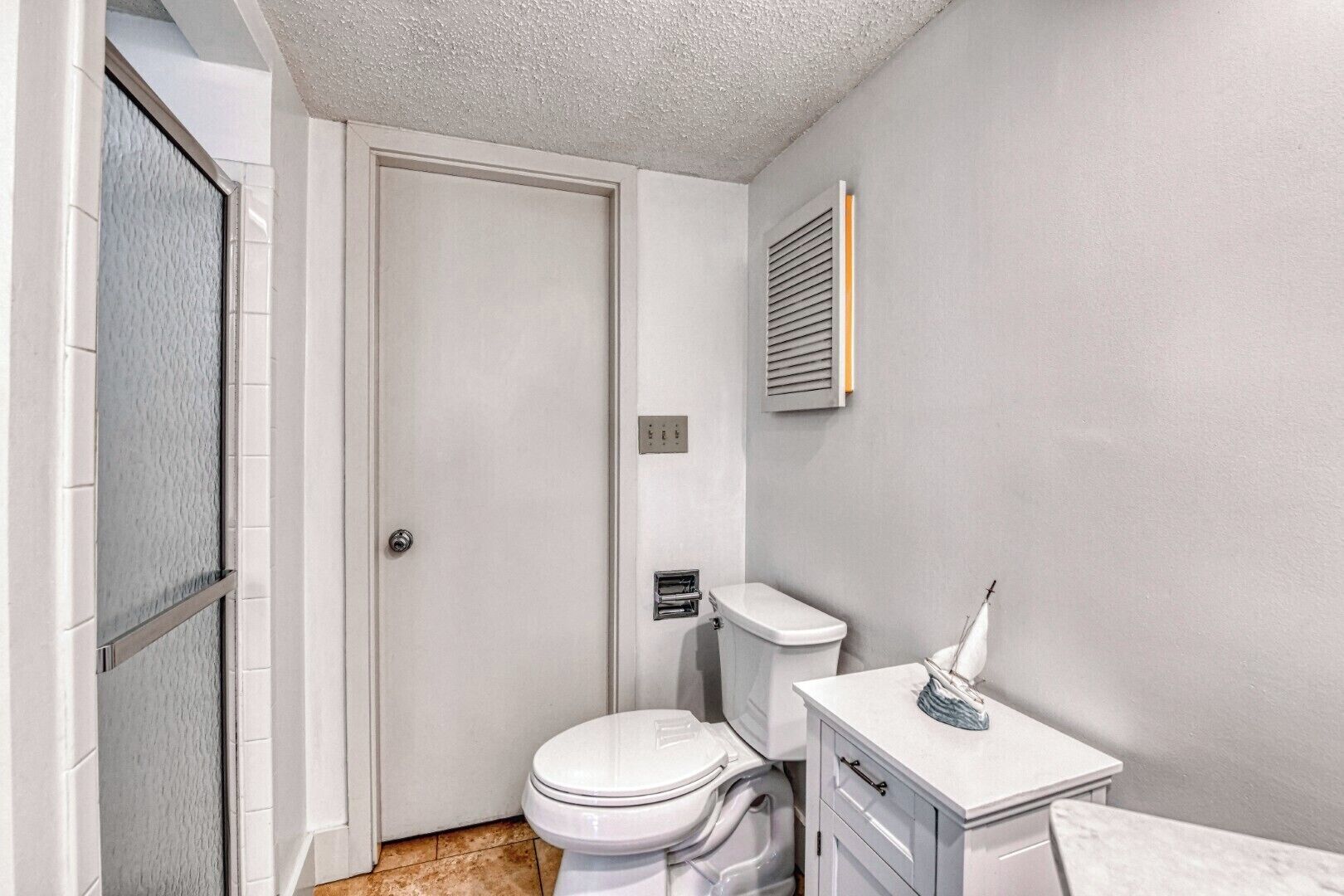 A small, clean bathroom with a toilet, sink, and a door leading to another room.
