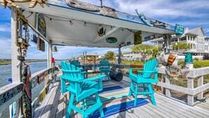 Una terrazza coperta con poltrone Adirondack color turchese, un tappeto a righe e diverse decorazioni a tema nautico.