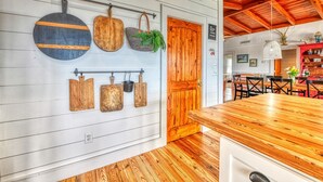 Una cucina con piani di lavoro in legno, un portaspianne a sospensione e una porta in legno.