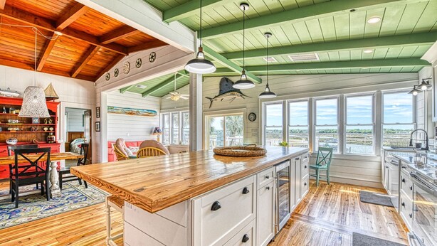 Un'ampia cucina con una grande isola, pavimento in legno e vista sull'esterno grazie a ampie finestre.