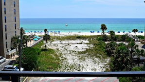 A beach view with a building, palm trees, and a clear sky.