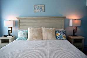 A bedroom with a wooden headboard, a white quilted bedspread, and two bedside tables with lamps.