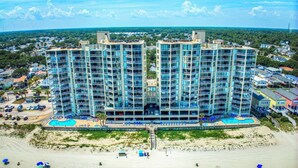Un hotel moderno con numerosi balconi, una zona piscina e vista sulla spiaggia.